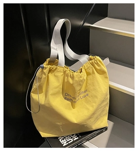 Detail of yellow nylon drawstring tote with Dream Together Remember Love text print