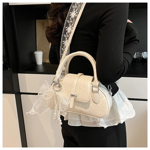 Detail of beige Boston bag with floral embroidered strap and pearl lace bow accessory