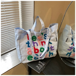Detalle del bolso tote de lona azul claro con letras flocadas de colores y etiqueta