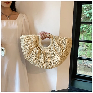 Minimalist beige woven straw tote bag held by a model in a summer vacation scene
