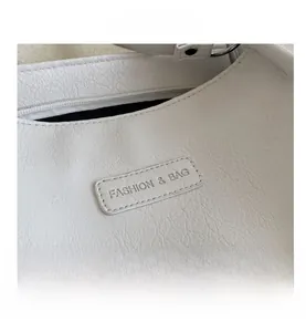 Close-up of white lychee grain leather tote bag with embossed fashion brand label tag