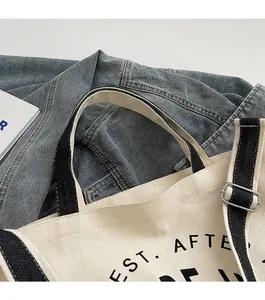 Détail du sac cabas en toile avec anses noires et boucle de réglage en métal