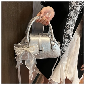 Detail of silver shell bag featuring a white mesh bow and exquisite pearl beads