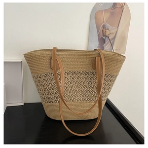 Detailed close-up of straw tote bag showing hollow-out texture and leather handles