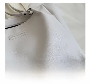 Close-up of white tote bag with lychee grain texture and Fashion & Bag logo detail