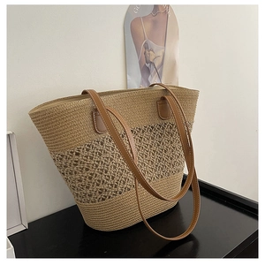 Detail of woven straw tote bag featuring hollow pattern and brown leather handles