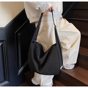 Detailed shot of black high-density nylon hobo bag with wide adjustable strap on model