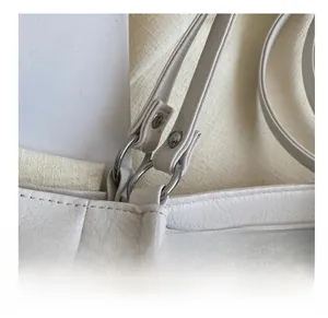 Detail of silver O-ring connector and studs on white lychee leather tote bag strap