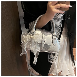 Silver metallic pillow bag detail with pearl bow charm and elegant shoulder strap