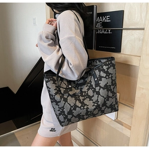 Detail van een grote shopper met zwart en grijs abstract patroon en luxe leren biesjes