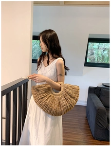 Chic large straw tote bag in half-moon shape paired with an elegant white summer dress