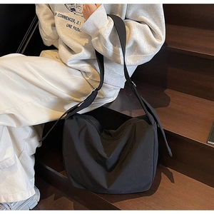 Detail view of black nylon tote bag with wide adjustable strap on a female model