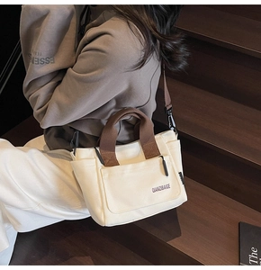 Detail van canvas crossbodytas met bruine geweven handvatten en verstelbare schouderriem