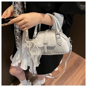 Detail of silver metallic shell bag with organza bow and pearl handle decoration
