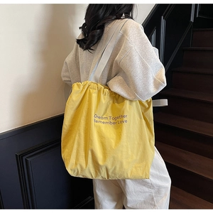 Detail of yellow drawstring canvas tote bag with purple lettering Dream Together text