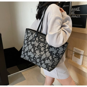Detail van een grote shopper tas met grijze koeienprint textuur en zwarte schouderbanden