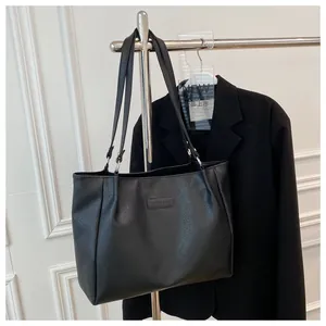 Detail of black pebbled leather tote bag with Fashion & Bag logo and silver hardware