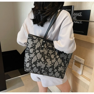 Detail van grote shopper met artistieke grijze steenprint en zwarte handvatten