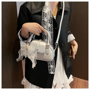 Detail view of silver shell bag with mesh bow and pearl charm for a stylish look