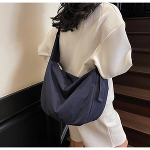 Detail of navy blue crescent-shaped shoulder bag showing large capacity and nylon texture