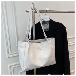 Close-up of a white tote bag with fine grain texture and fashion metal brand nameplate