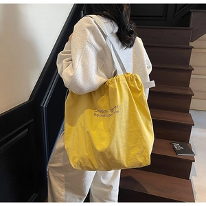 Close-up of bright yellow drawstring tote bag with printed text on nylon material