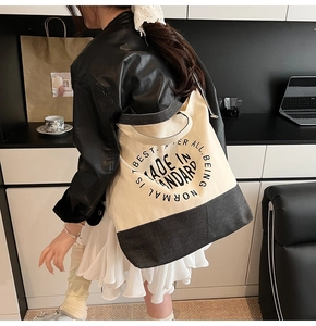 Détail du sac cabas en toile contrastée avec imprimé noir vu de profil latéral