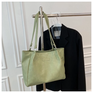 Close-up of light green PU leather tote bag with FASHION & BAG lettering and fine texture