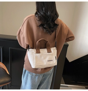 Detail van de minimalistische canvas shopper met bruine handgrepen en voorvak voor werk