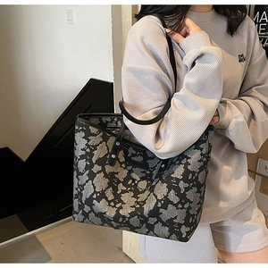 Detail van de grote tote bag met koeprint en versterkte metalen klinknagels aan de riem