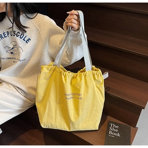 Detail of bright yellow canvas tote bag with purple lettering and drawstring closure