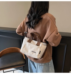Detail van minimalistische canvas crossbodytas met bruine handvatten en schouderriem