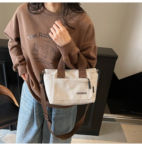 Detail van witte canvas crossbodytas met bruine riemen en voorvak voor dagelijks gebruik