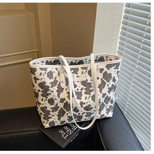 Detailweergave van grote shopper met koeprint en witte handvatten op getextureerd oppervlak