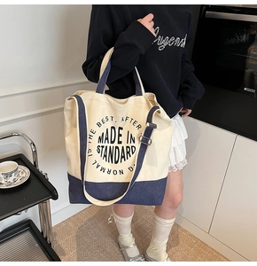 Détail d'un grand sac cabas en toile beige et bleu marine avec bandoulière réglable