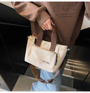 Detail van minimalistische beige canvas crossbodytas met bruine banden en voorvakje