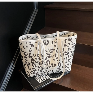 Detailopname van de draagtas met dierenprint en metalen logo op getextureerd leer