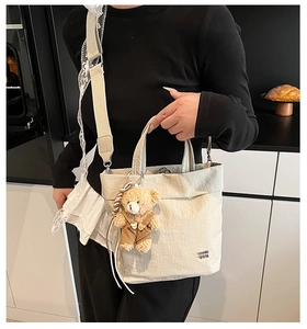 Detail of beige canvas tote with cute teddy bear pendant and black letter embroidery