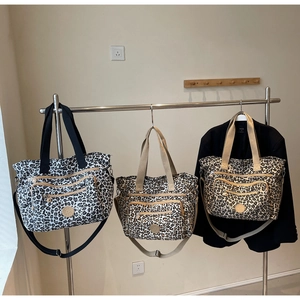 Detail of leopard print tote bags with decorative zippers and adjustable straps