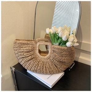 Detail of handmade woven straw handbag with tulips, showing natural texture and design