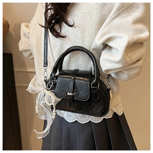 Detail of black pleated leather shell bag with white mesh bow and pearl charms