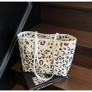 Detail van de tote bag met dierenprint, reliëf merklabel en lange handvatten