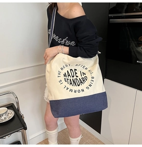 Détail du sac cabas en toile avec panneaux contrastés et texte circulaire imprimé