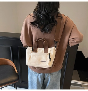 Detail van canvas crossbodytas met beige body, bruine riemen en ritsvak aan de voorkant