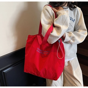 Detail view of large red canvas tote with Dream Together lettering and drawstring side