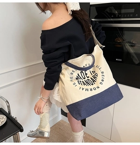 Détail du sac cabas en toile montrant le contraste du tissu et la boucle en métal réglable