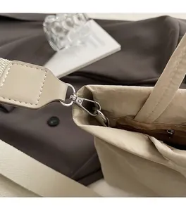 Detailed view of silver lobster clasp and woven strap on a beige textured canvas tote bag