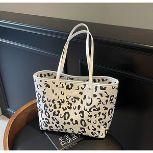 Detail van de grote tote bag met koeienprint, ledertextuur en zilveren klinknagels