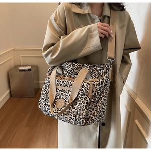 Detailed close-up of leopard print canvas tote bag featuring double front zip pockets