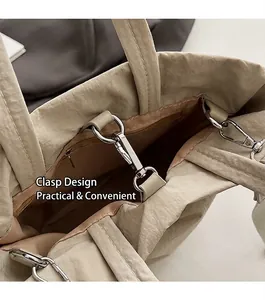 Detail of the beige tote bag showing the silver metal buckle and interior zipper pocket